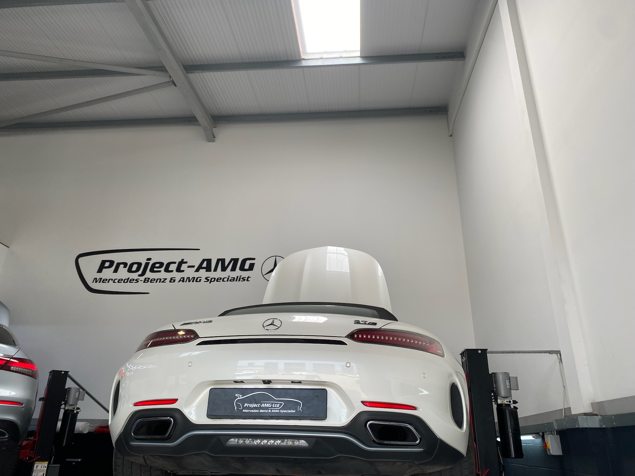 Rear view of a white Mercedes-AMG sports car on a lift at Project-AMG garage, a Mercedes-Benz & AMG specialist